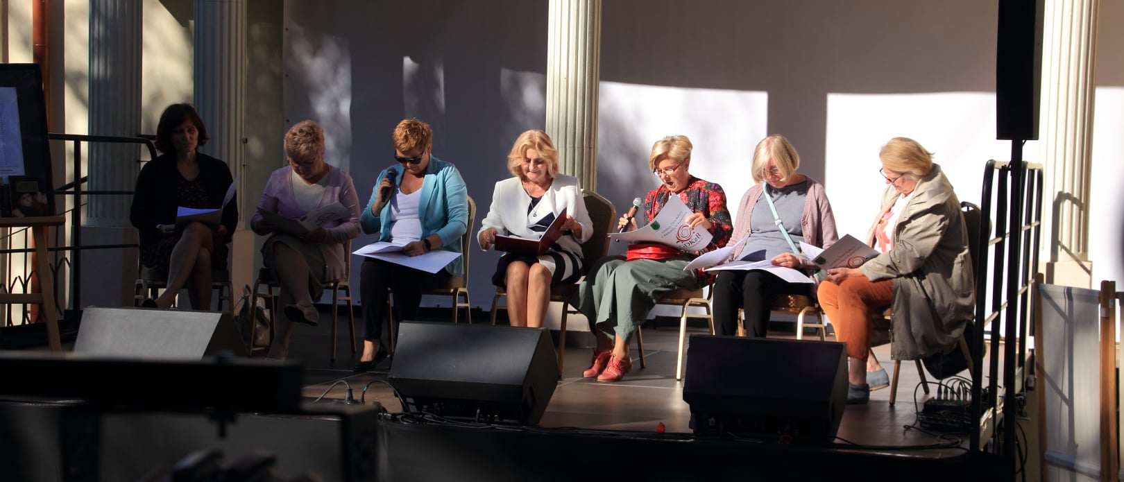 Na zdjęciu siedem kobiet siedzących na krzesłach na scenie, podczas Narodowego Czytania