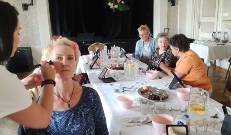 kobiety siedzą przy stole, jedna z pań ma robony makijaż