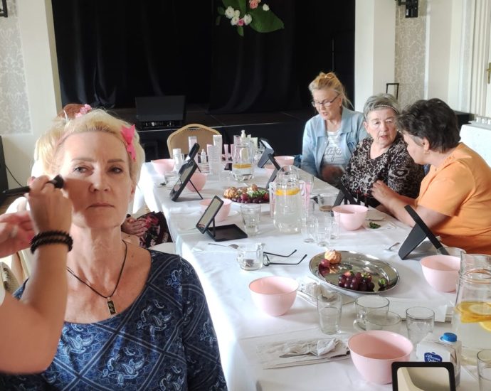 kobiety siedzą przy stole, jedna z pań ma robony makijaż