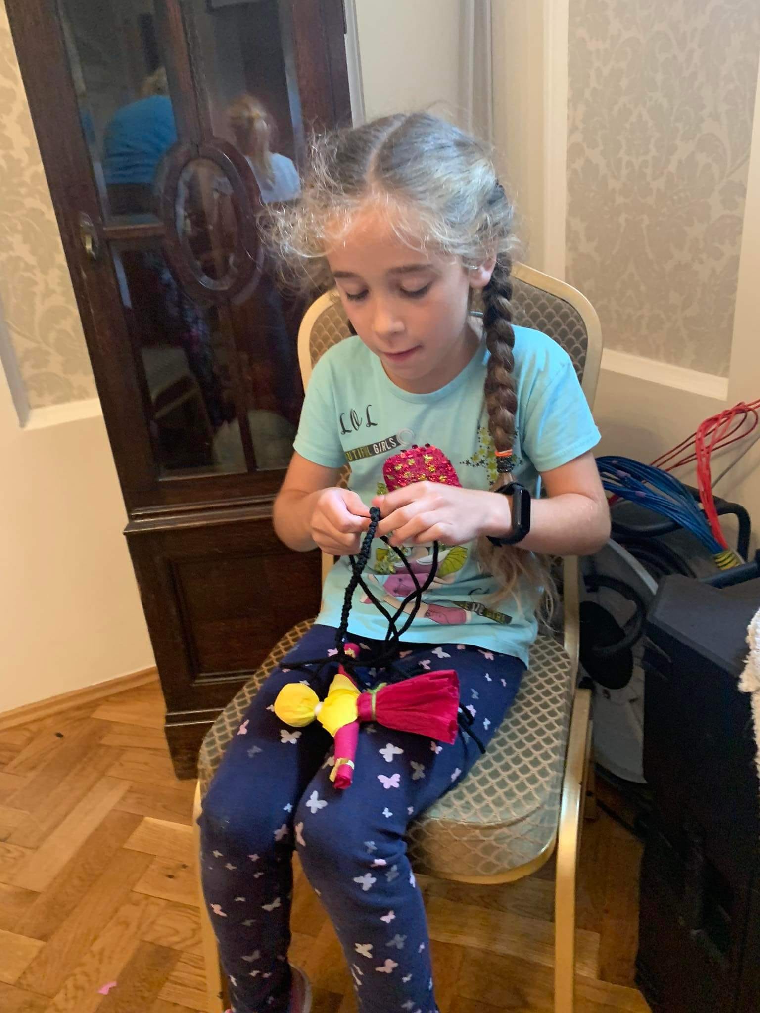 dziewczynka zaplata warkoczyki swojej lalce ze szmatek