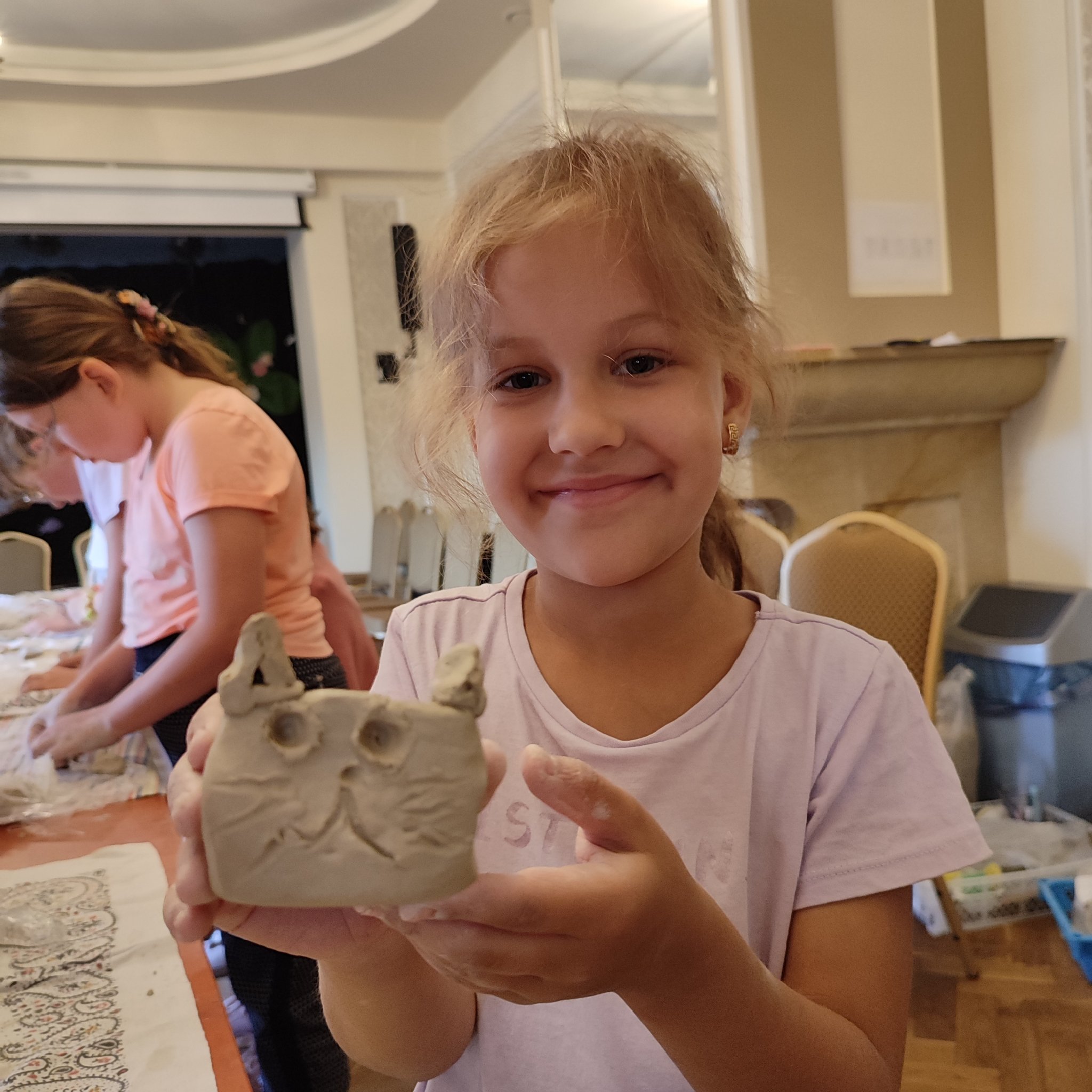 dziewczynka trzyma kotka wyrzeźbionego z gliny