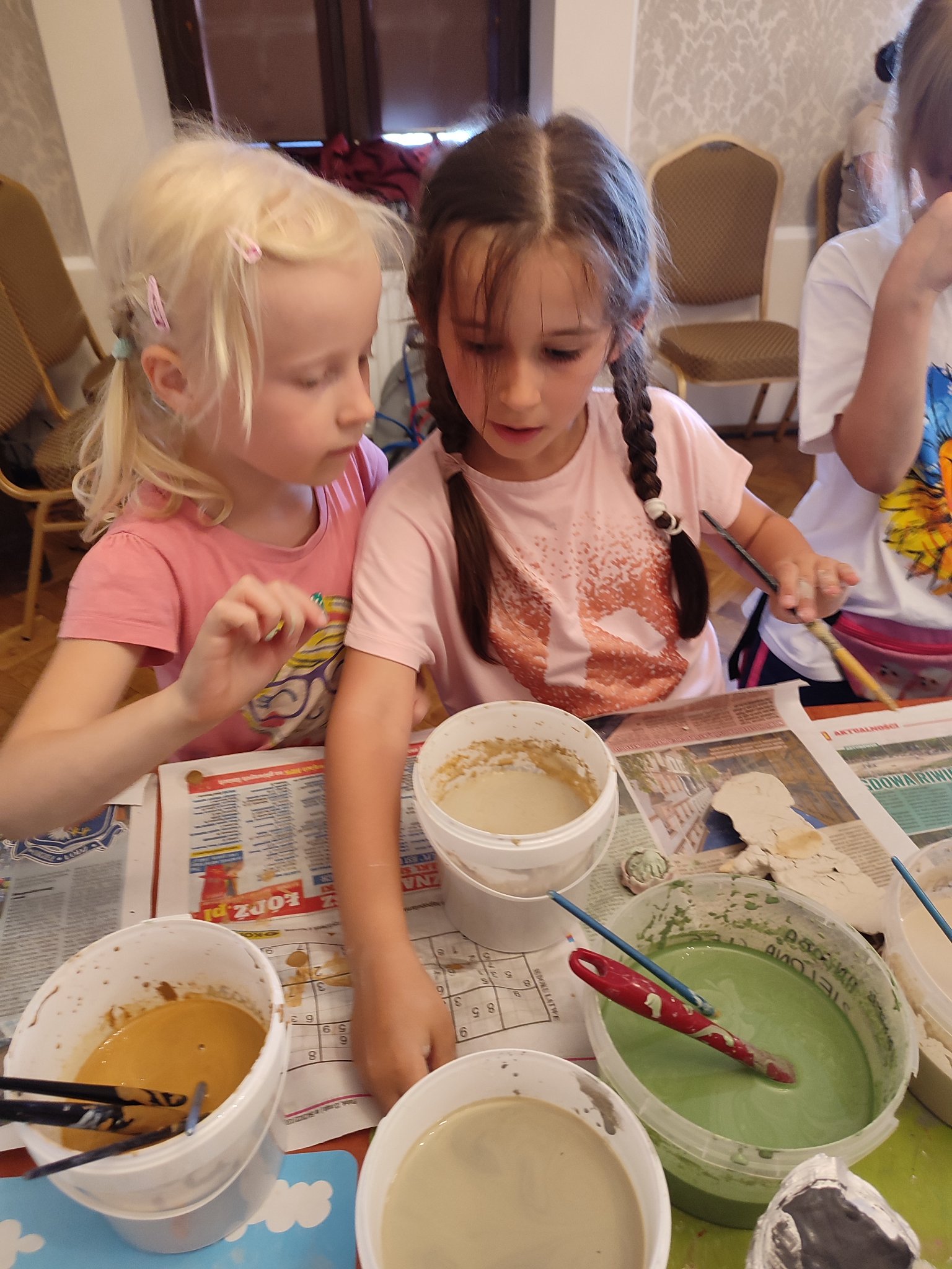 dwie dziewczynki malujące swoje pracy z gliny