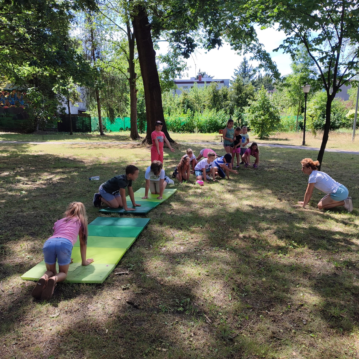 dzieci w parku ćwiczące na materacach