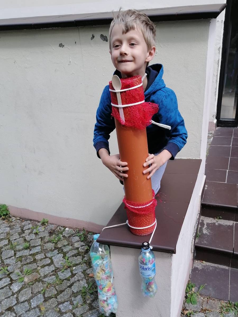 Chłopiec stojący na murku trzymający stworzoną przez siebie rakietę
