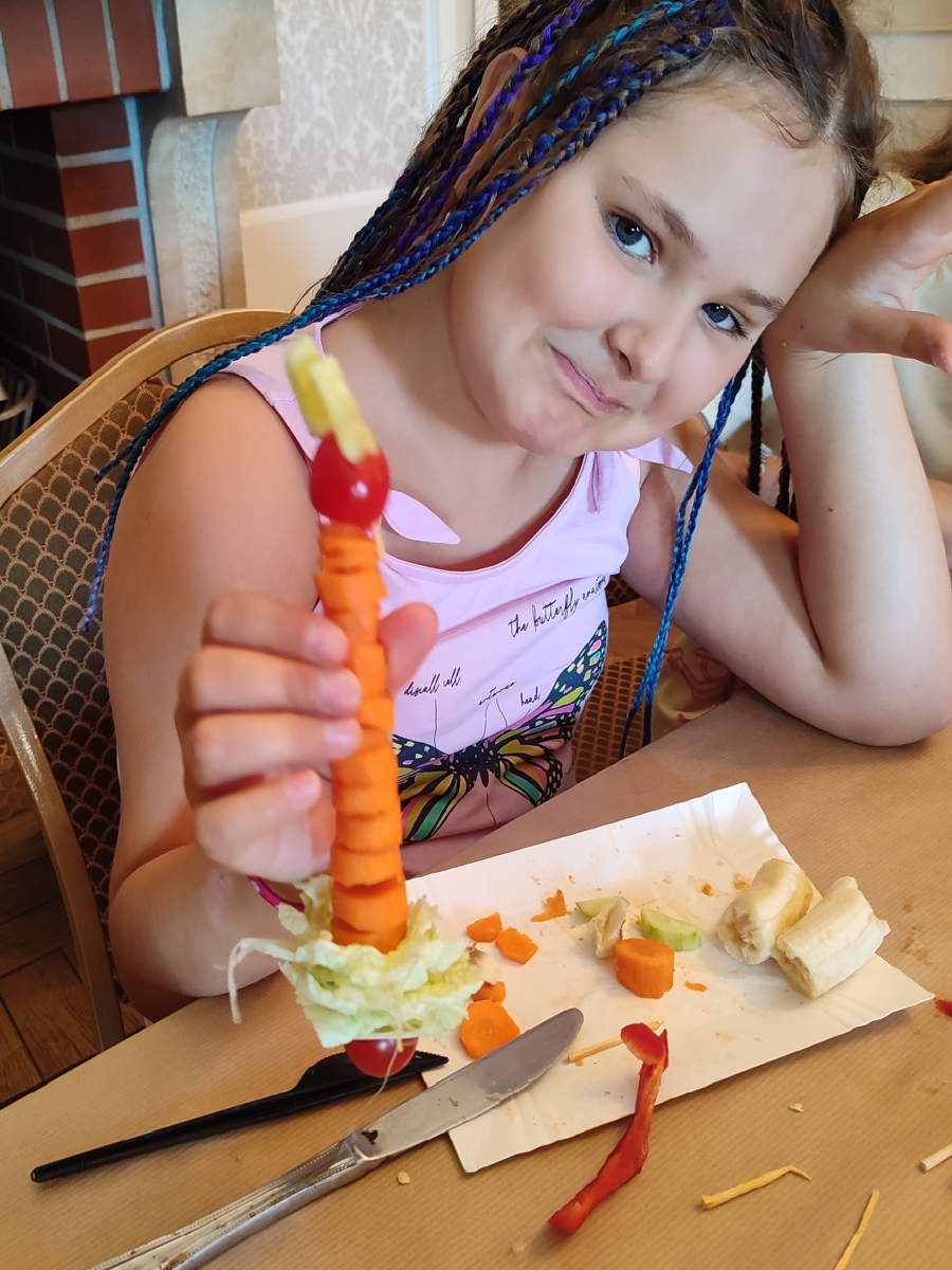 dziewczynka trzyma zrobioną przez siebie rzeźbę z warzyw