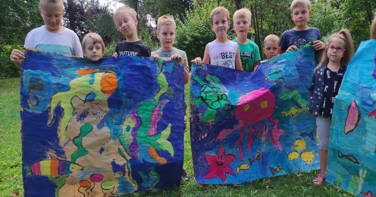 dzieci trzymają stworzone przez siebie prace przedstawiające podwodny świat