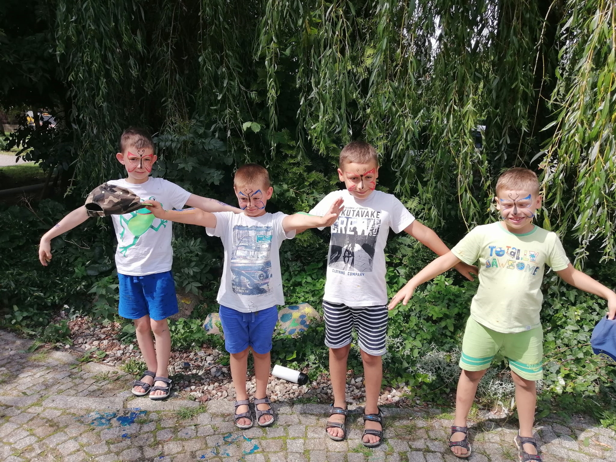 czterech chłopców z pomalowanymi w motyle buziami