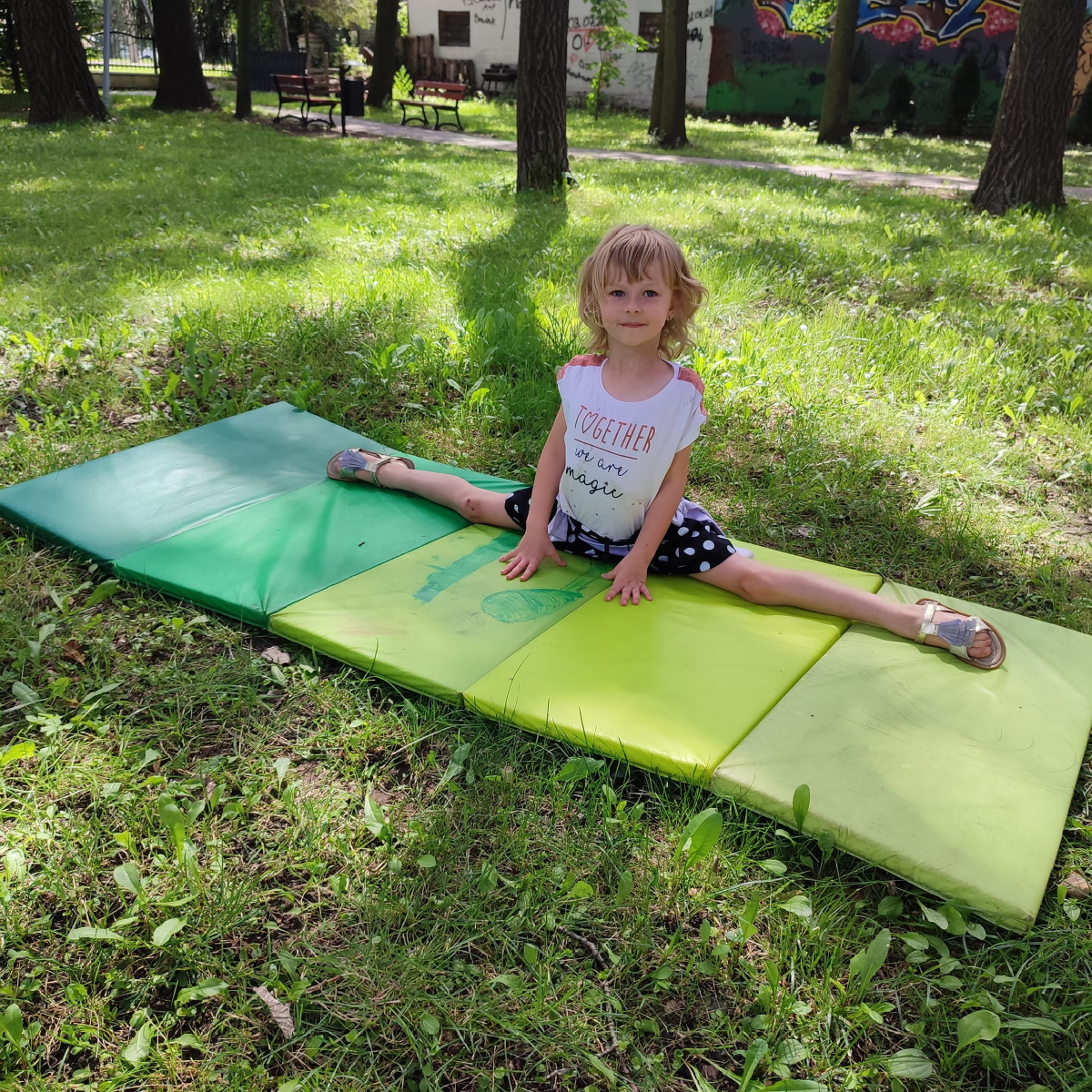 dziewczynka robiąca szpagat w parku