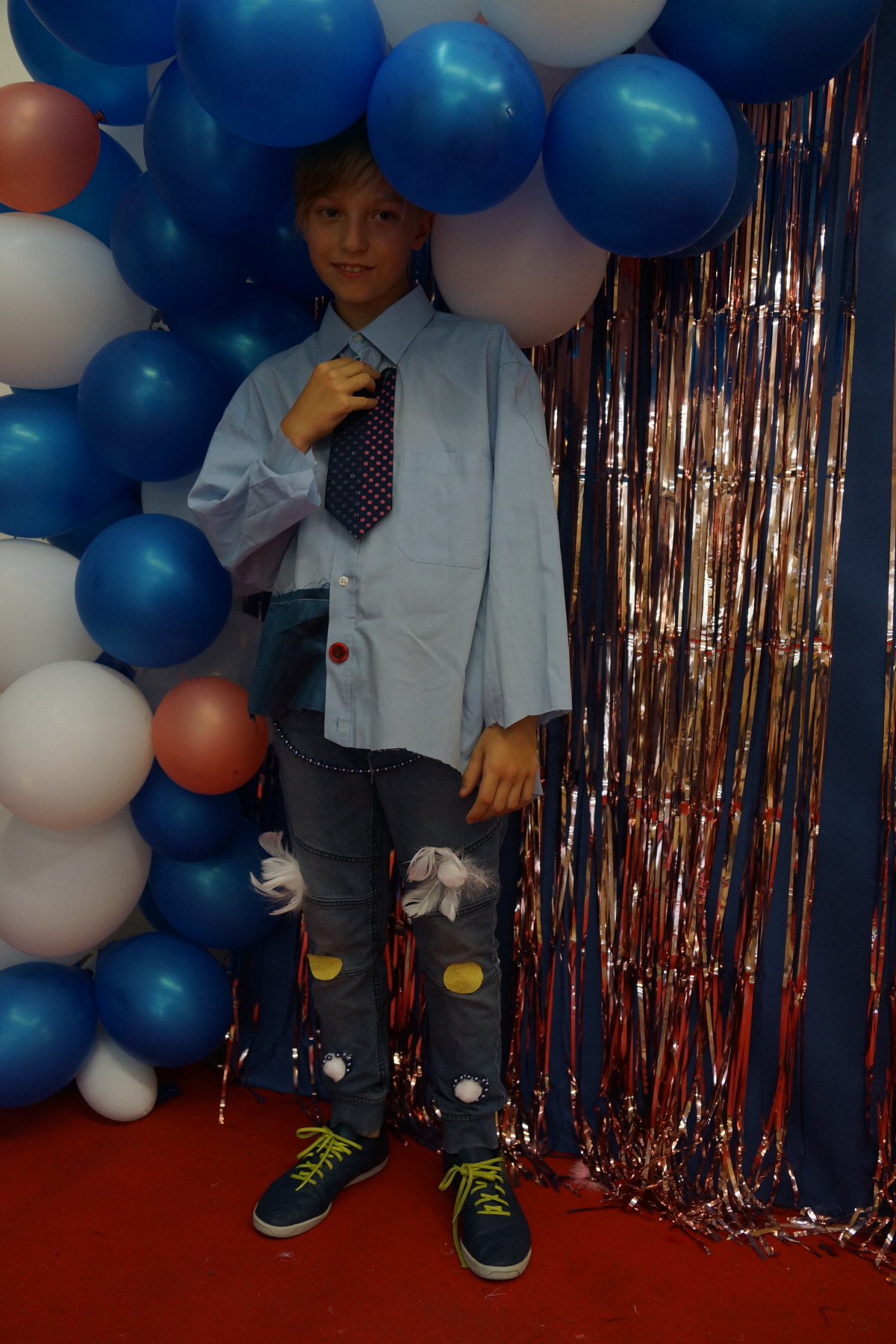 na zdjęciu chłopiec w niebieskiej kszuli w tle balony