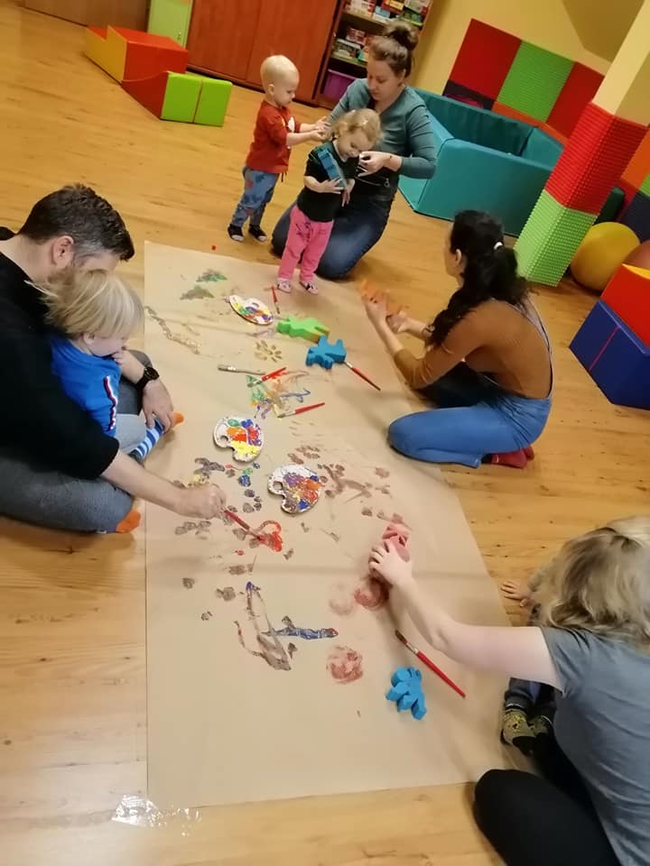 dzieci wraz z rodzicami przy kartonie z farbami 