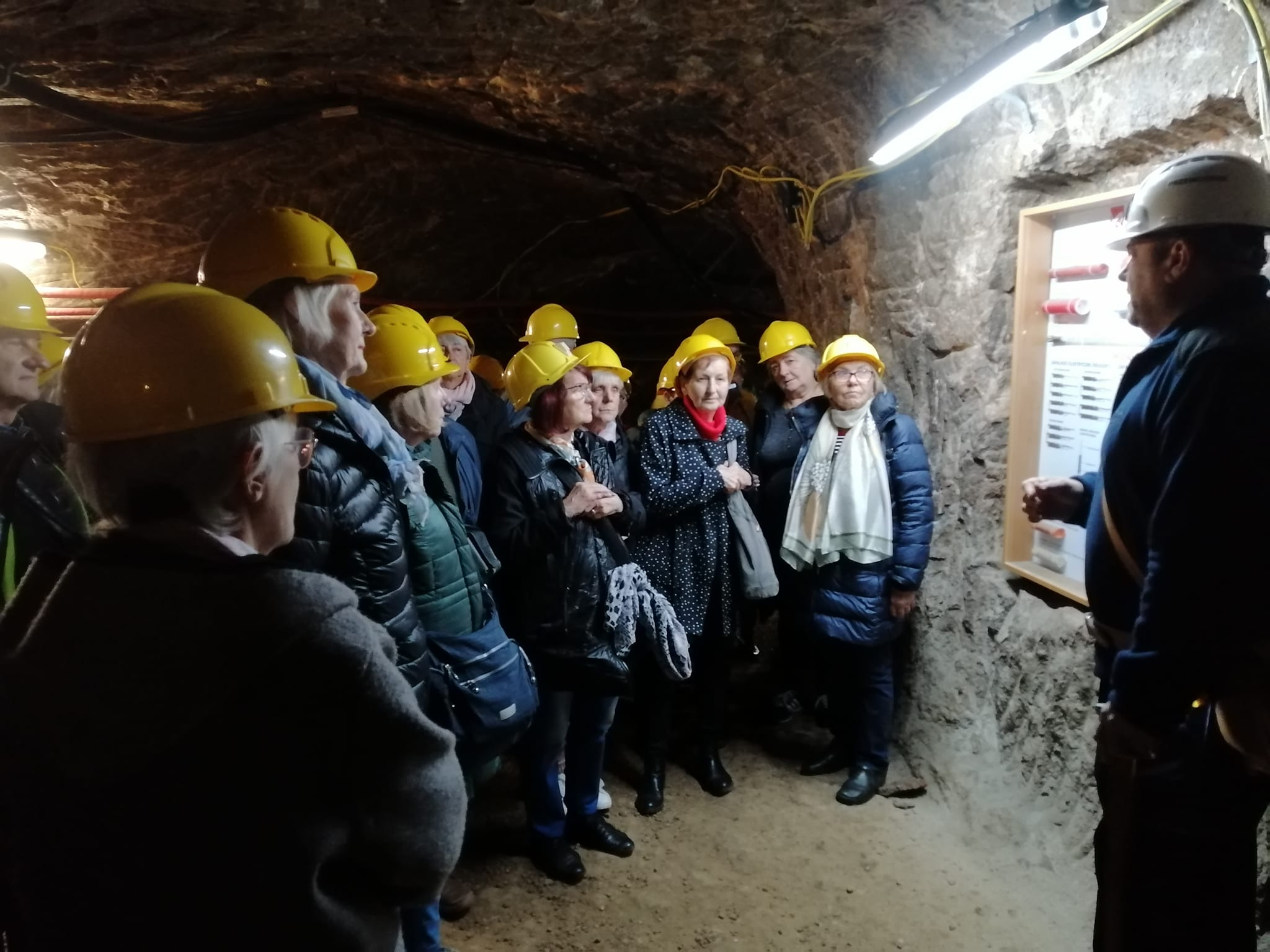 grupa seniorów w kopalni soli. seniorzy stoją przed górnikiem który opowiada